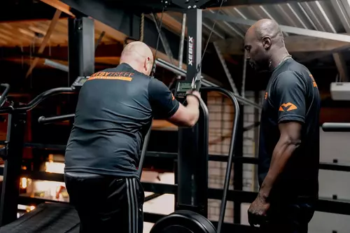 Twee dames trainen samen techniek tijdens een kickboksles. Één leerling trapt een lowkick en de andere verdedigt de lowkick met een block.