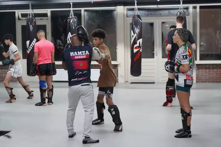 Een groep mensen die kickboksen beoefenen op de sportschool van Fightmasters. Op de achtergrond zijn bokszakken zichtbaar.